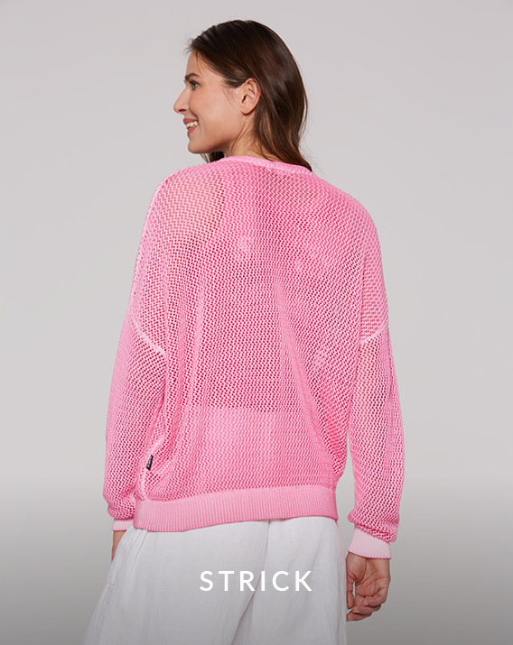 langer pinker Strick- Pullover getragen von einem Model mit weißer Leinenhose