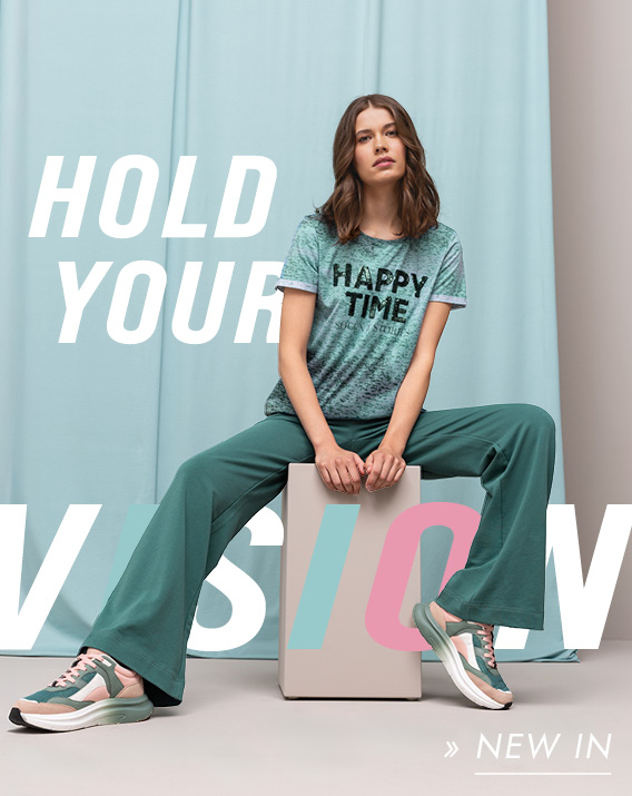 Model sitzt und hat Shirt und Hose aus neuer Kollektion an
