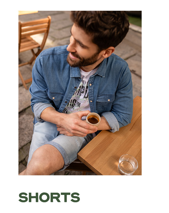 Model trägt ein Jeans Outfit und sitzt im Cafe.